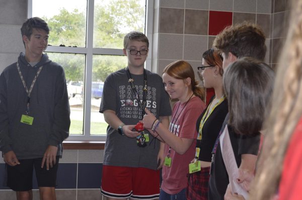 Engaged in a lively hallway circle discussion about substance abuse, Mrs. Howsmon’s advisory class fosters open communication. With a thumbs-up freshmen, Taytum Kimball passes the talking tool—a red stress ball—to freshman, Haven Harrington, enabling him to contribute thoughtful dialogue and active participation. (Photo by Sarene Andrius-Walker)