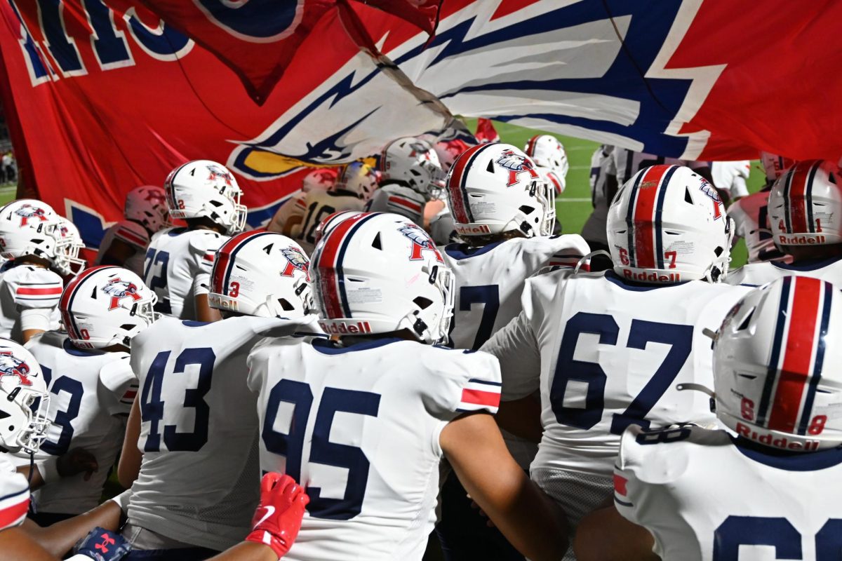 The football team breaks through the banner to start the Katy game.